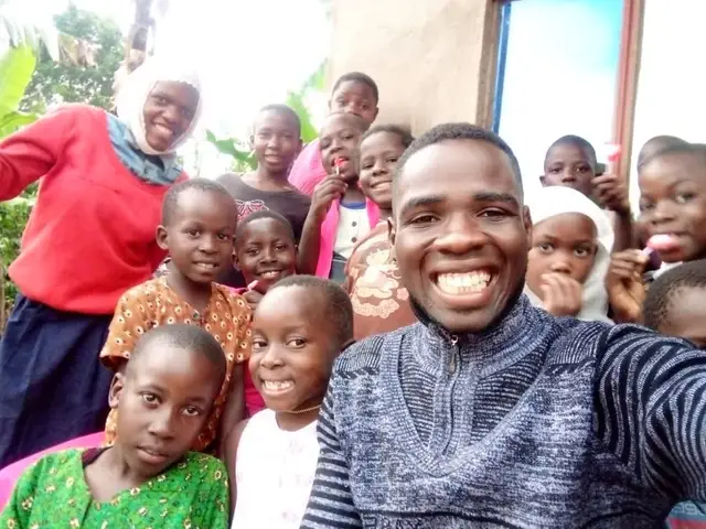 A caregiver taking a selfie with a dozen smiling children