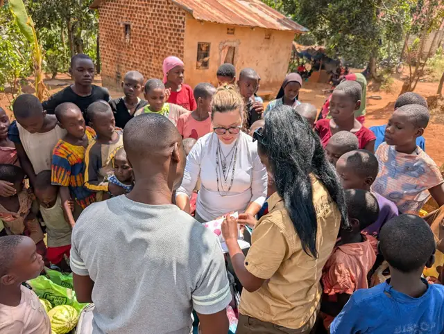 A woman handing out supplies to families gathered around her
