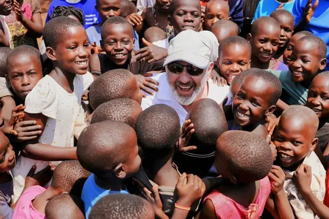 Jeff Hoffman smiling in the middle of a circle of children